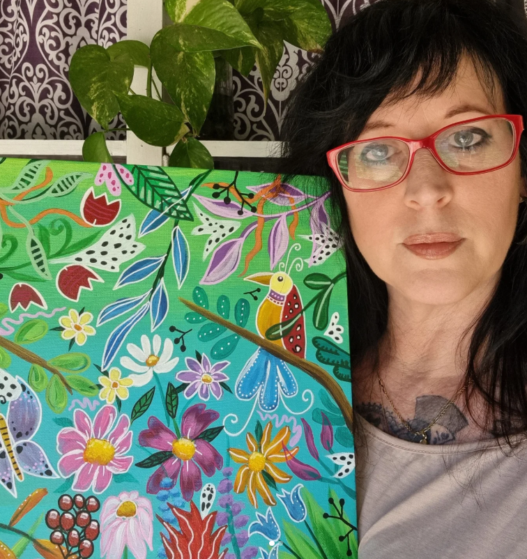artist holding acrylic painting of bird and flowers